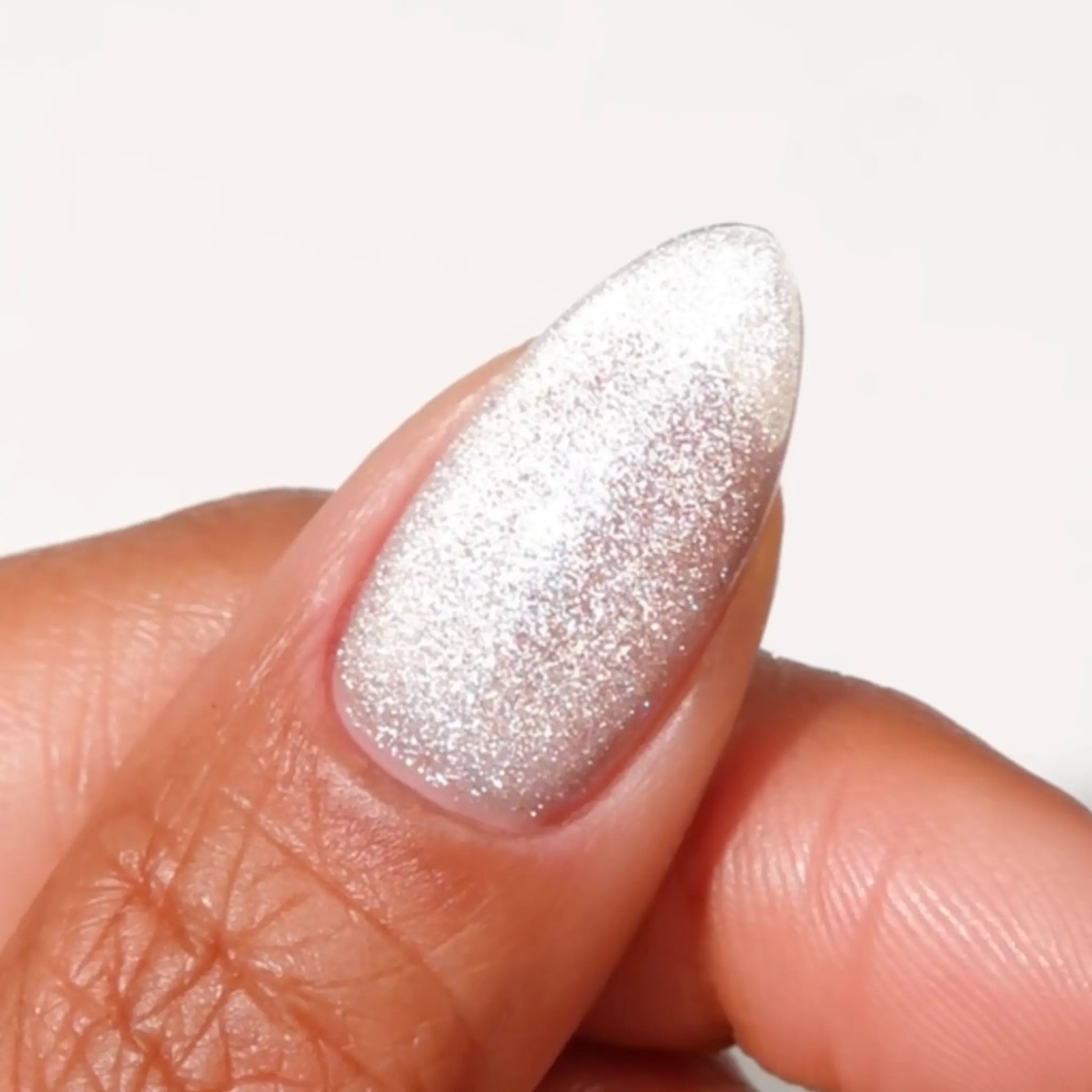 Finger with medium almond nails wearing Chrome Cat warm silver cat eye nail polish