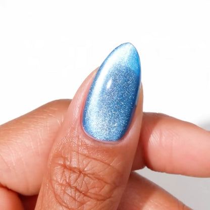 Finger with medium almond nails wearing great catsby vibrant blue cat eye nail polish