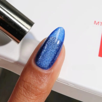 Finger with medium almond nails wearing paw and order blue cat eye nail polish with magnetic effects