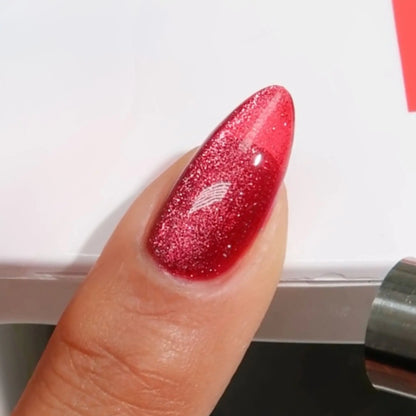Finger with medium almond nails wearing meowroon pinkish red cat eye nail polish with magnetic effects