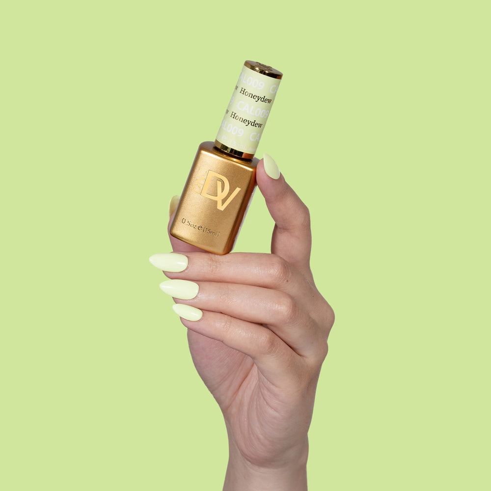 Hand holding gold-capped bottle labeled Honeydew, green background