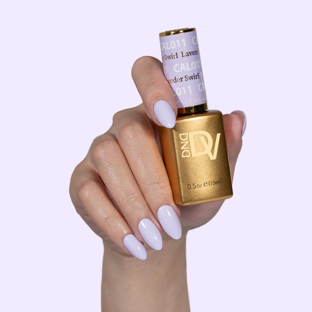 Hand with pale nails holding gold-capped bottle labeled Lavender Swirl, lavender background