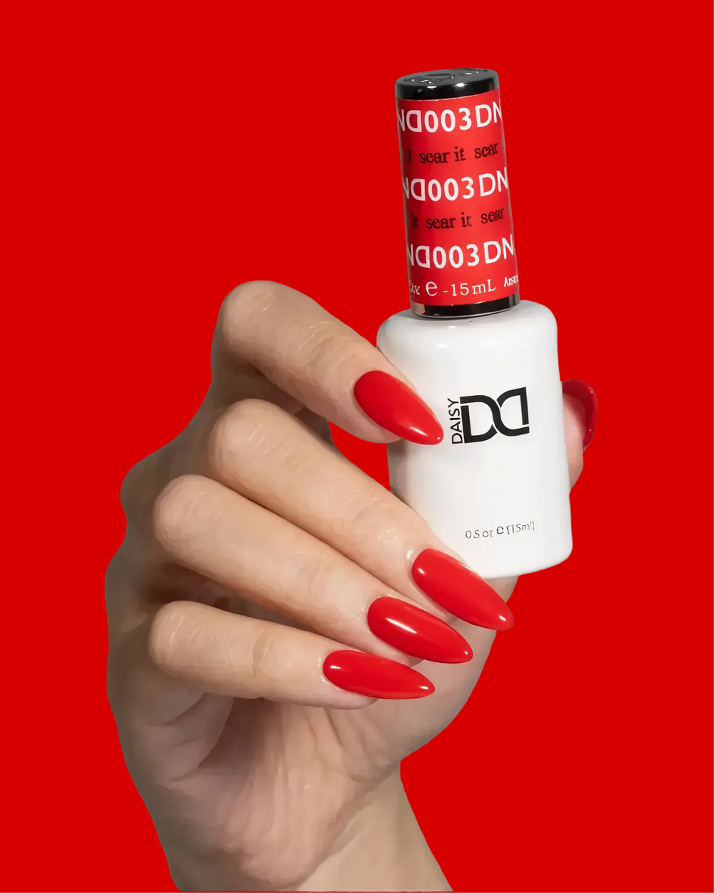 Hand with bright red nails holding a DND gel polish bottle labeled "Sear It"