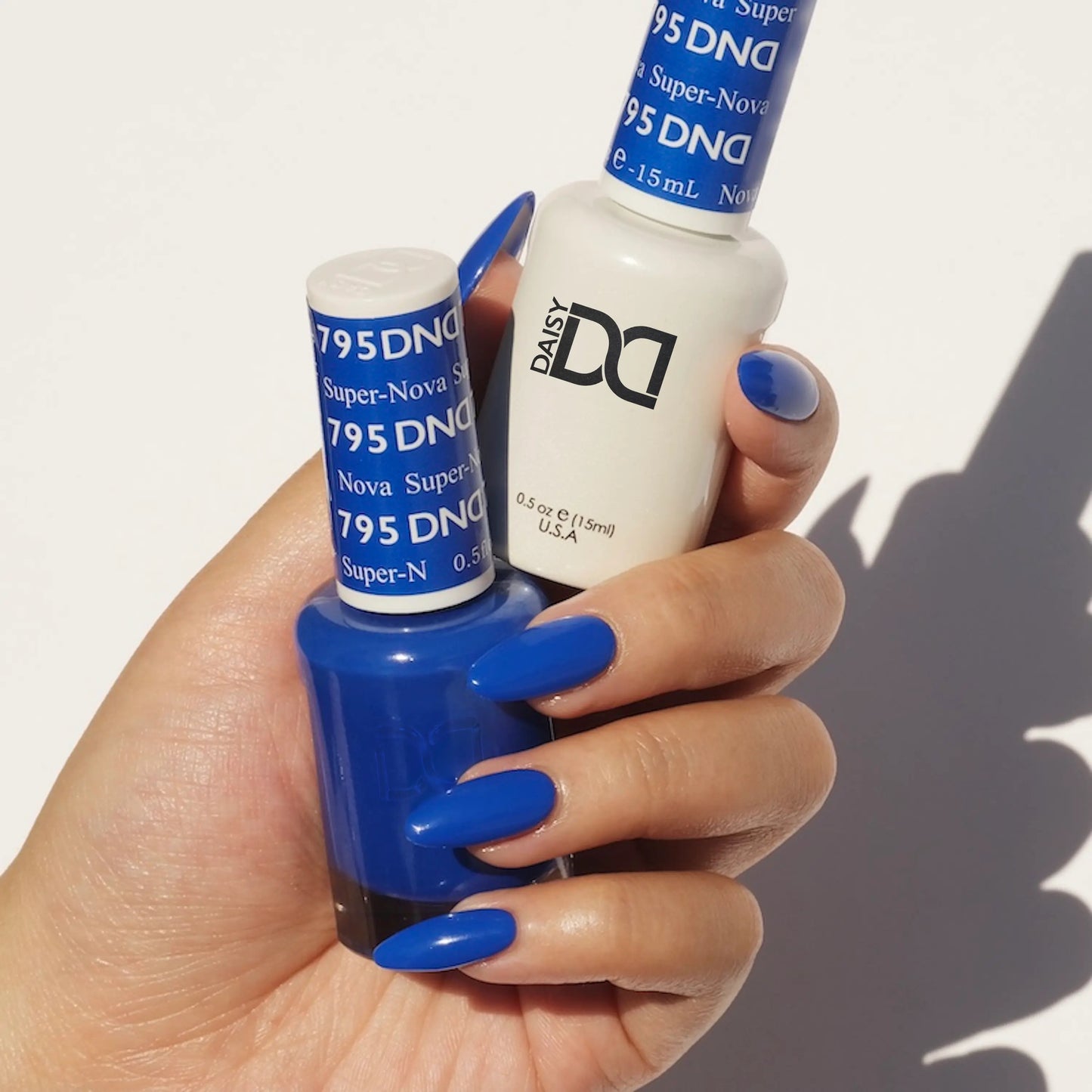 Hand holding two bottles of blue nail polish